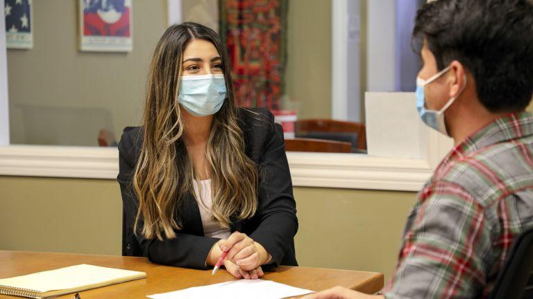 A female student is seated at a desk while wearing a mask