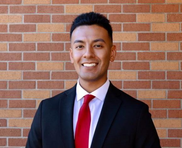 A portrait of a man wearing a suit in front of a brick wall